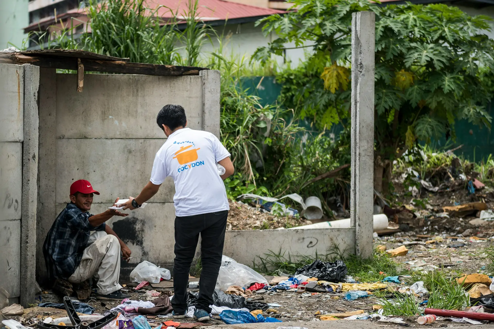man giving food on man sitting on corner of wall